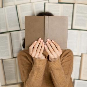 Person hinter Buch versteckt