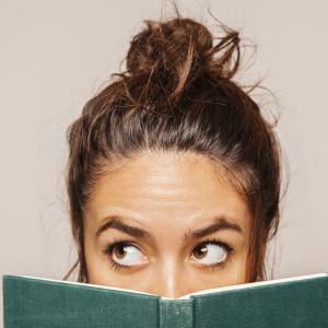 Frau halb hinter Buch versteckt